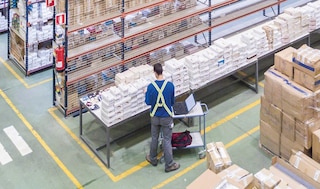 A worker checks products in the warehouse with the help of an electronic device