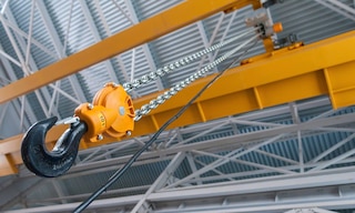 A warehouse overhead crane is used to handle heavy and bulky loads in a logistics facility A warehouse overhead crane is used to handle heavy and bulky loads in a logistics facility