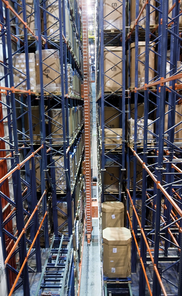 In each aisle, the twin-mast stacker cranes move pallets between input and output conveyors and rack locations In each aisle, the twin-mast stacker cranes move pallets between input and output conveyors and rack locations