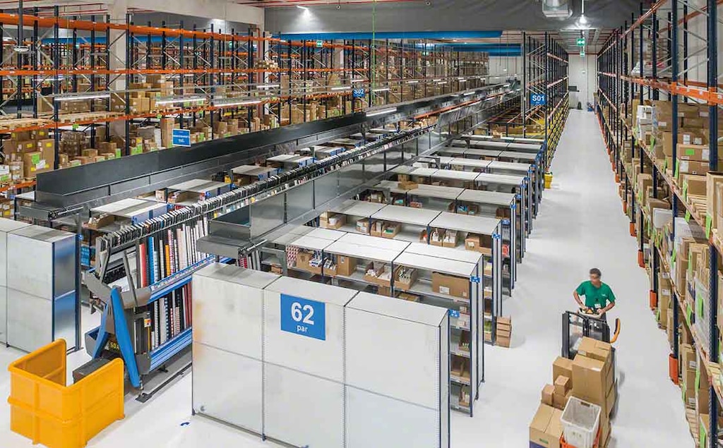 An operator performs warehouse picking tasks, aided by a pallet lorry An operator performs warehouse picking tasks, aided by a pallet lorry