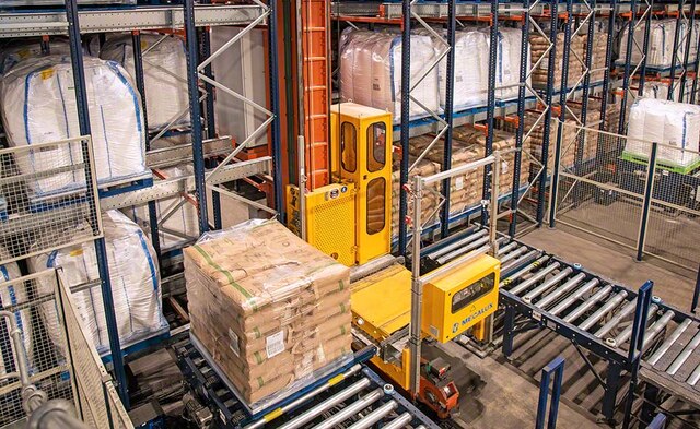 The stacker crane moves the pallets in the storage aisles