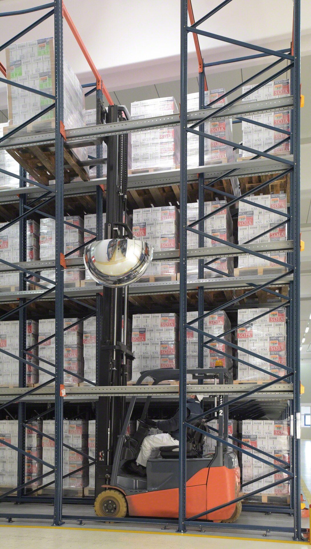 The forklifts travel inside the drive-in high-density racking with the load raised above the level on which it will be deposited