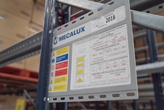 The signage plates, placed in visible areas of the drive-in pallet racking system, detail the technical characteristics of the racking