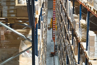 The stacker crane moves along the aisle to the location where it must deposit the pallet